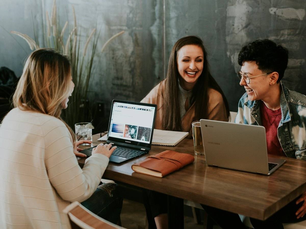Colleagues laughing together around a table with laptops