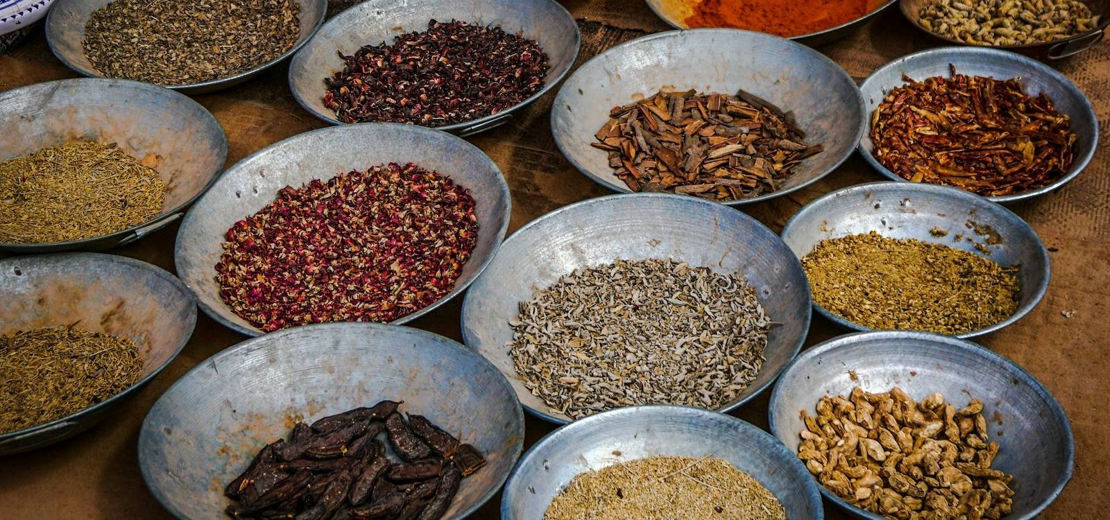 Bowls of whole spices and dried ingredients at a market stall