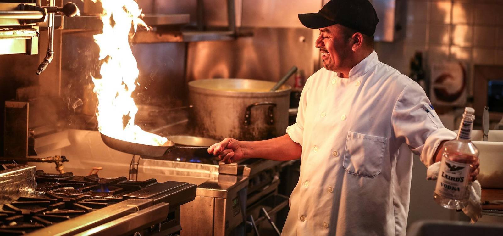 A chef cooking over a high flame in a professional kitchen