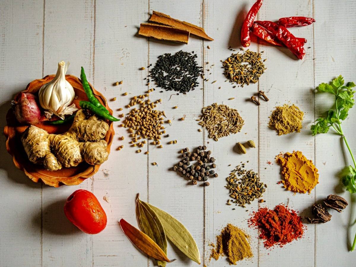 Whole spices, herbs and aromatics arranged on a white wooden table