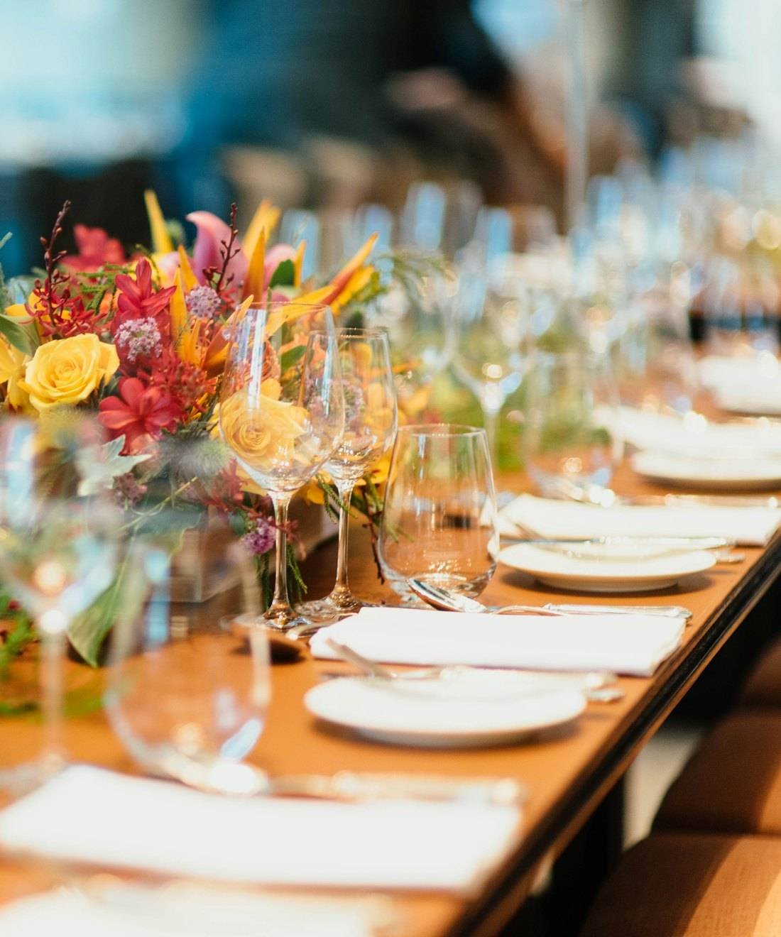 A long banquet table set with glassware and fresh flowers