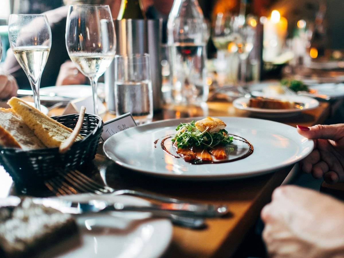 A plated dish being served at a candlelit dining table