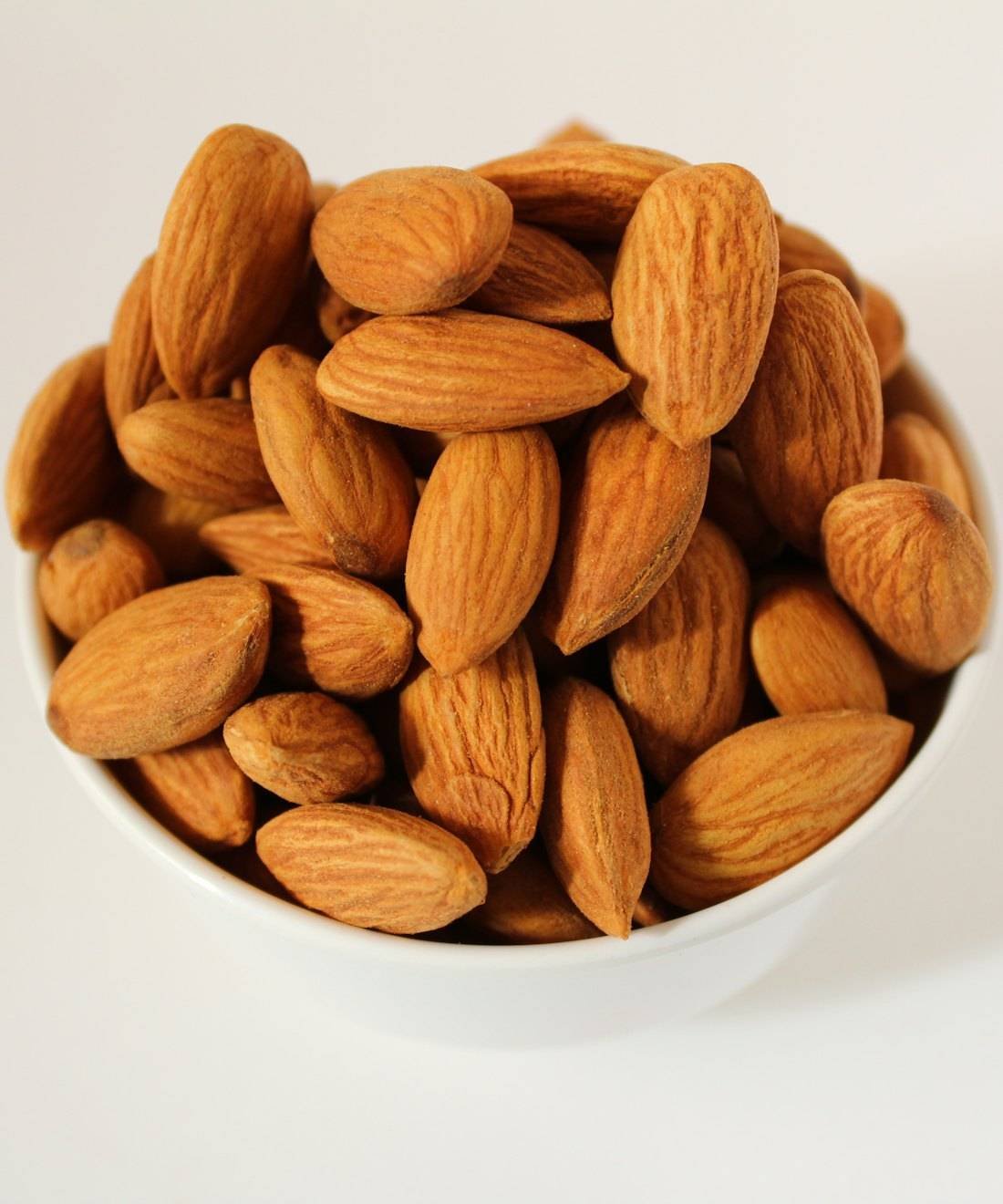 A white bowl filled with whole almonds